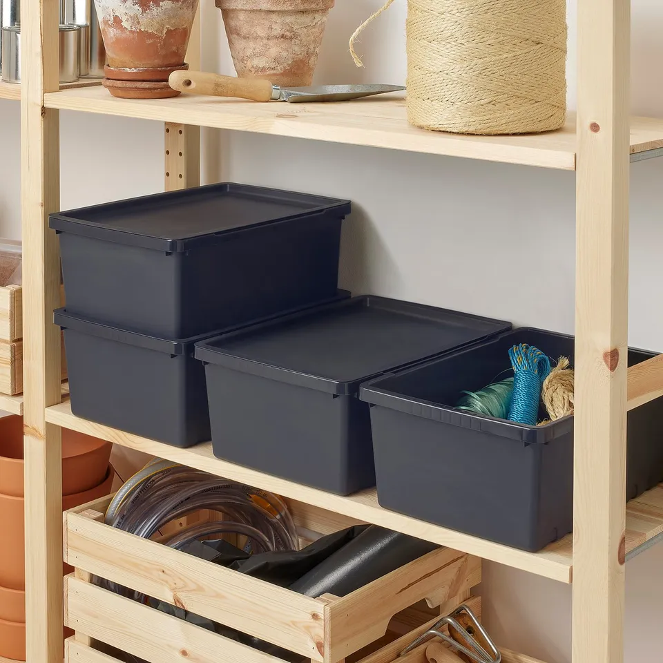 Dark blue recycled polypropylene boxes, rectangular, stackable, holding gardening tools on wooden shelves.
