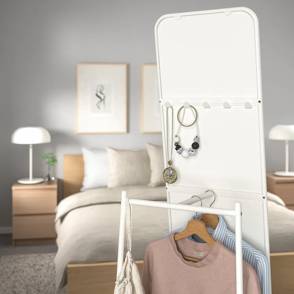 A bedroom scene with a KNAPPER mirror. The mirror hides hooks and a rail for hanging clothes and jewellery.