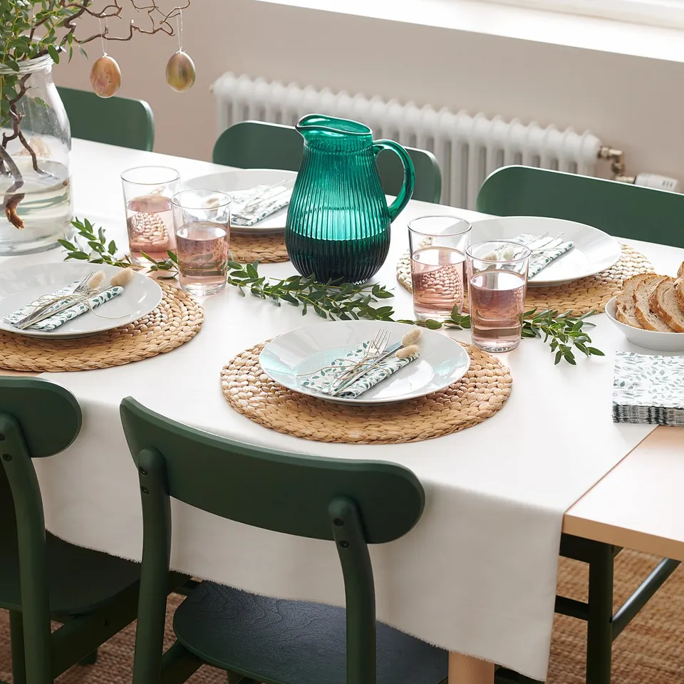 Elegant dining setup with green RÖNNINGE chairs, round placemats, white plates, and a green pitcher.