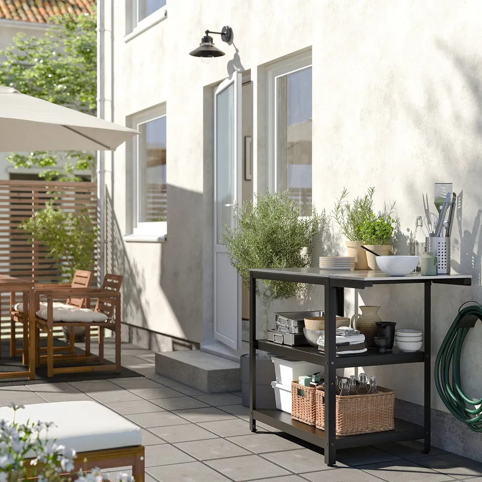 Modern outdoor kitchen setup with GRILLSKÄR stainless steel units, neutral tones, and potted plants.