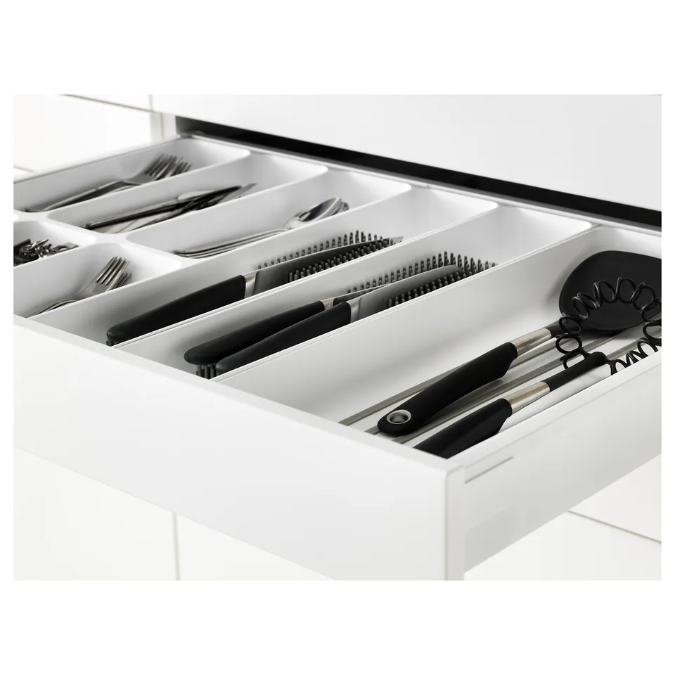 Open white kitchen drawer showing organised cutlery and utensils, with self-closing mechanisms.