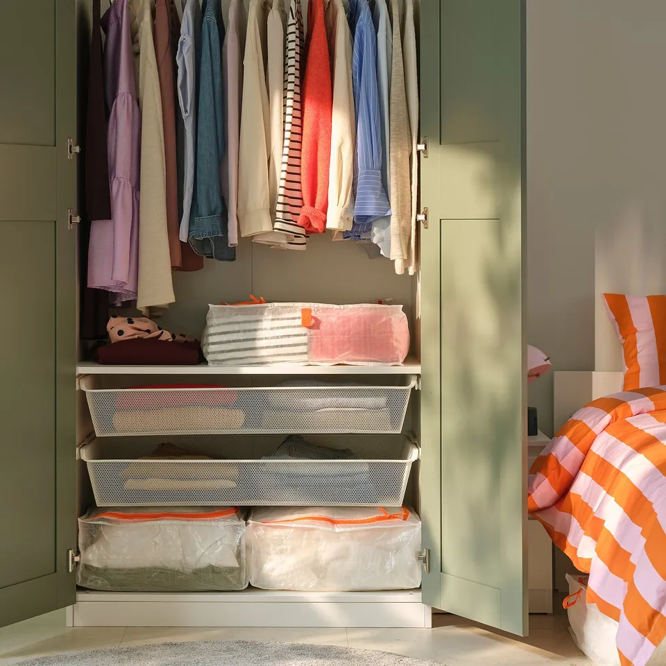Open closet shows clothes hung neatly, with folded linens in white cases on shelves.
