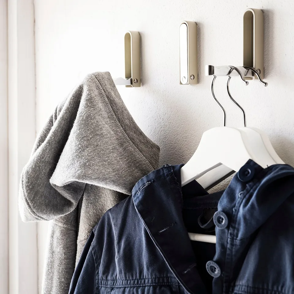 KLYKET hooks, silver metallic, triangular shape, holding grey sweater and navy jacket.