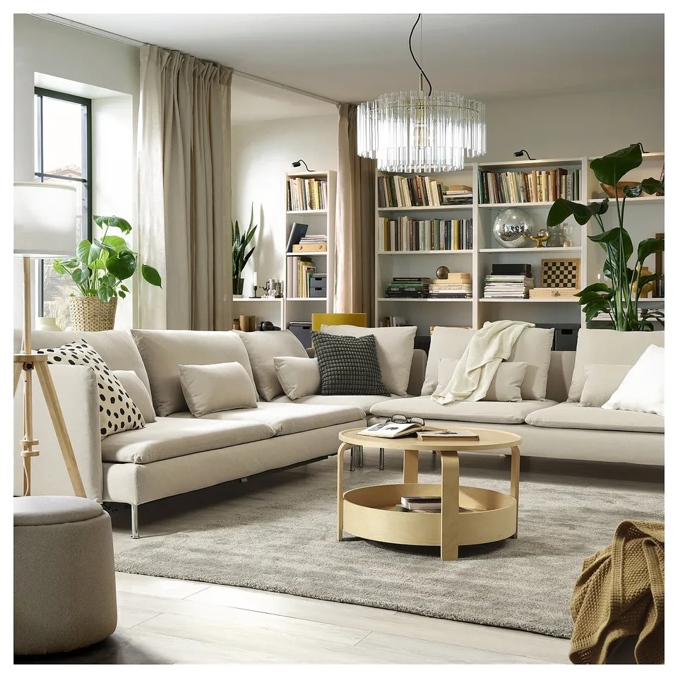 Modern living room with beige SÖDERHAMN sectional, coffee table, bookshelf, plants, and chandelier.