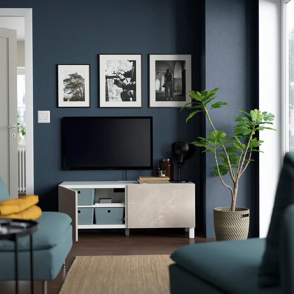 Modern living room with BESTÅ tv stand, featuring adjustable shelves for cable management, and a flat screen tv on a dark blue accent wall.