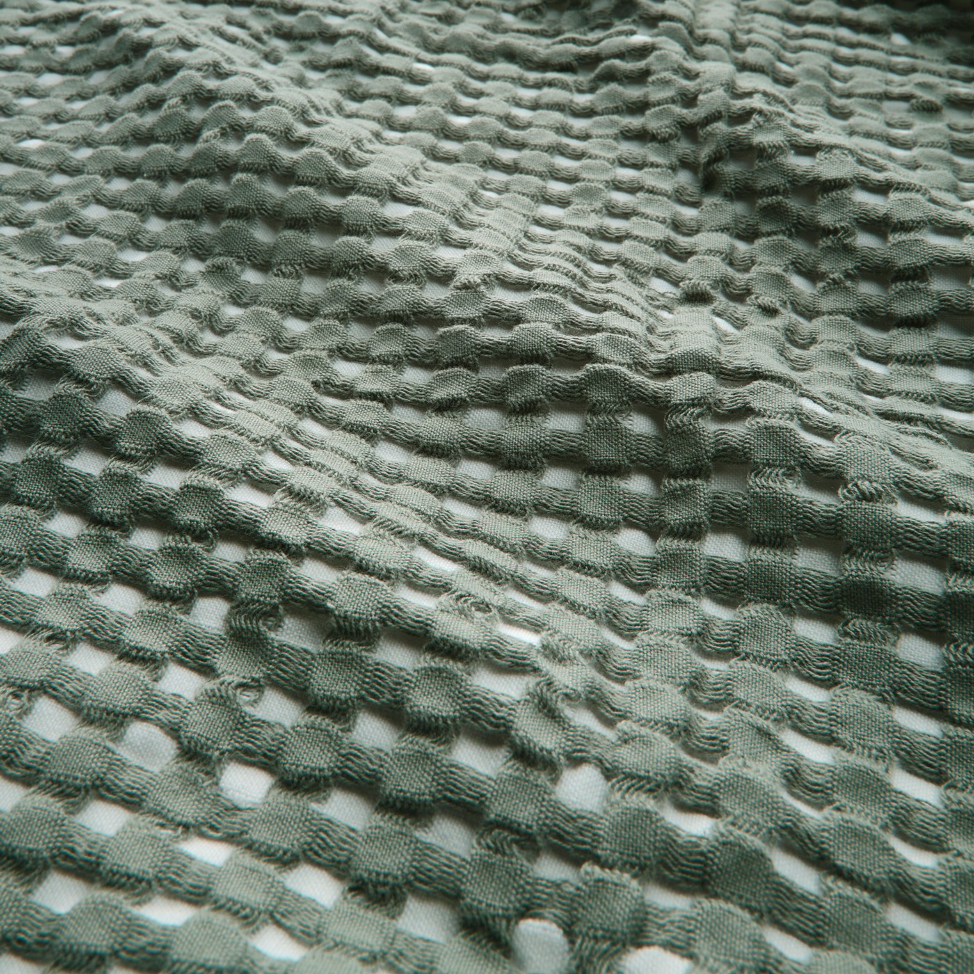 Soft green waffle weave cotton bedspread, double-sided, showing intricate texture.