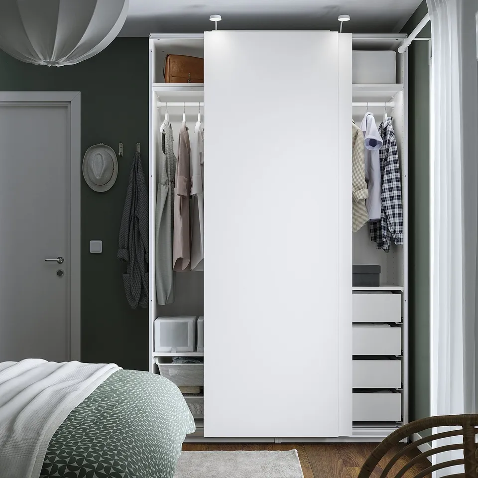 Modern bedroom with open wardrobe displaying clothes and accessories.