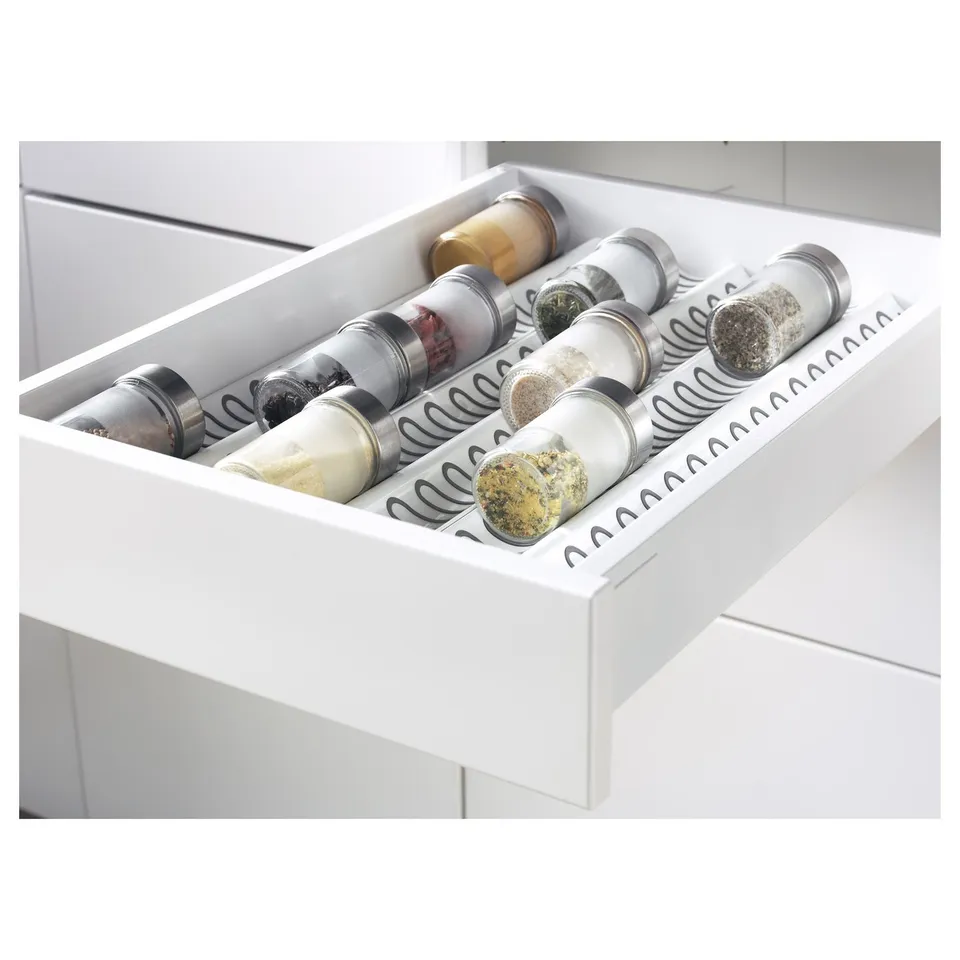 White kitchen drawer organiser holding spice jars, part of IKEAs METOD system.