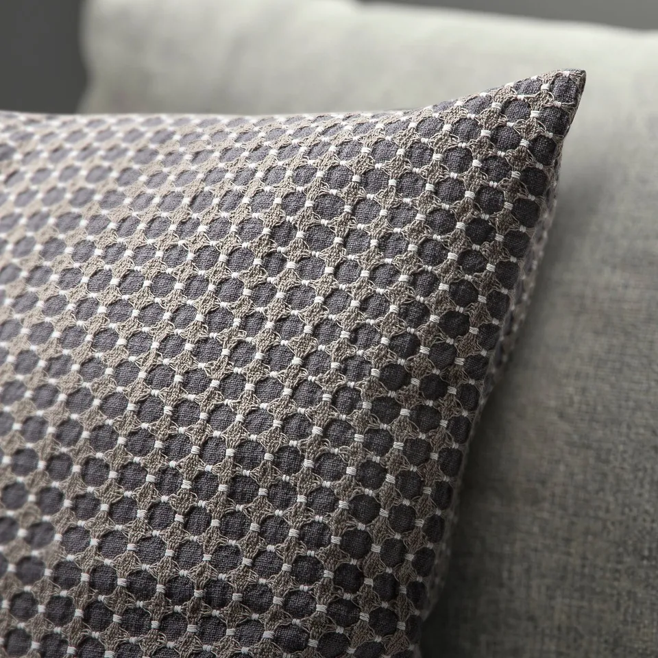 Textured cushion on couch, intricate geometric pattern in neutral tones.