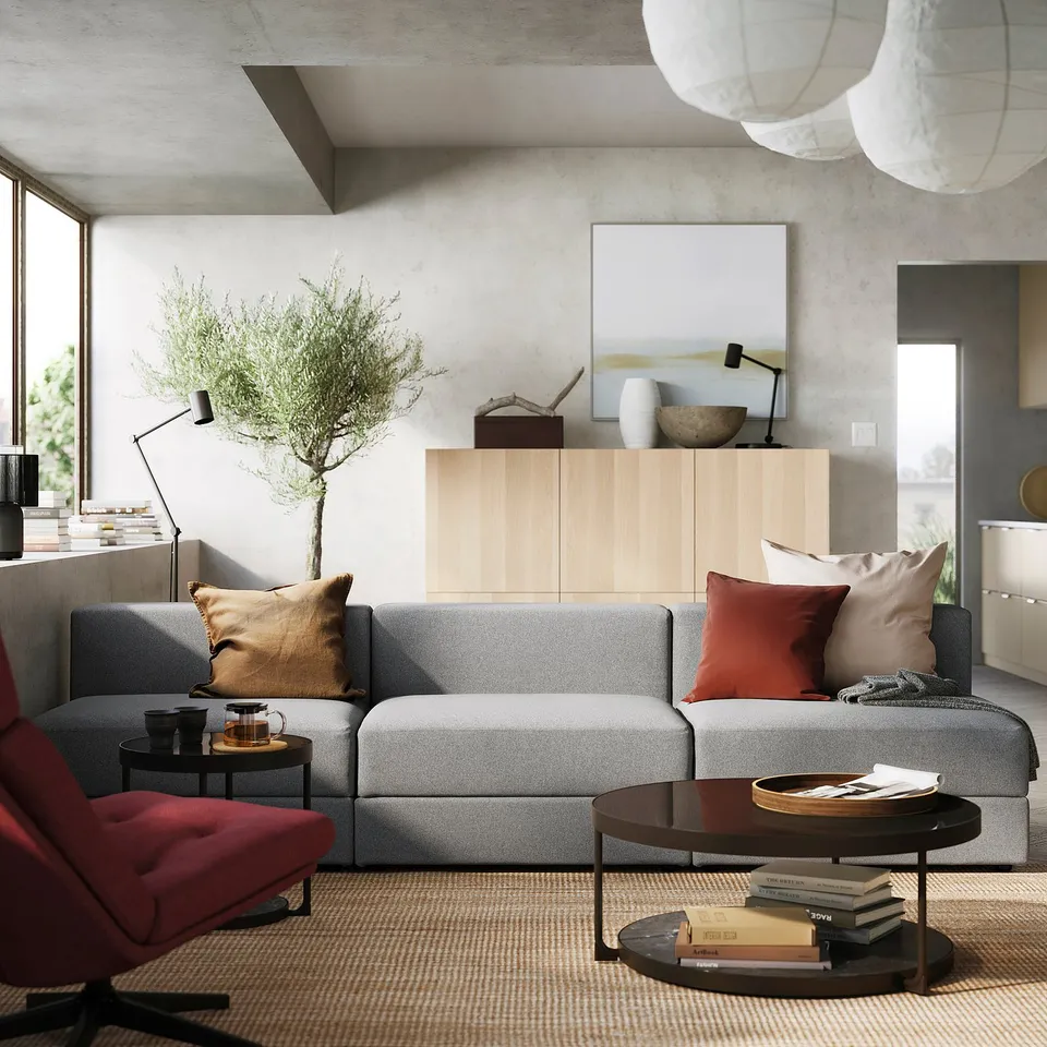 Modern living room with grey sofa, red accents, cabinet, coffee table, and large window.