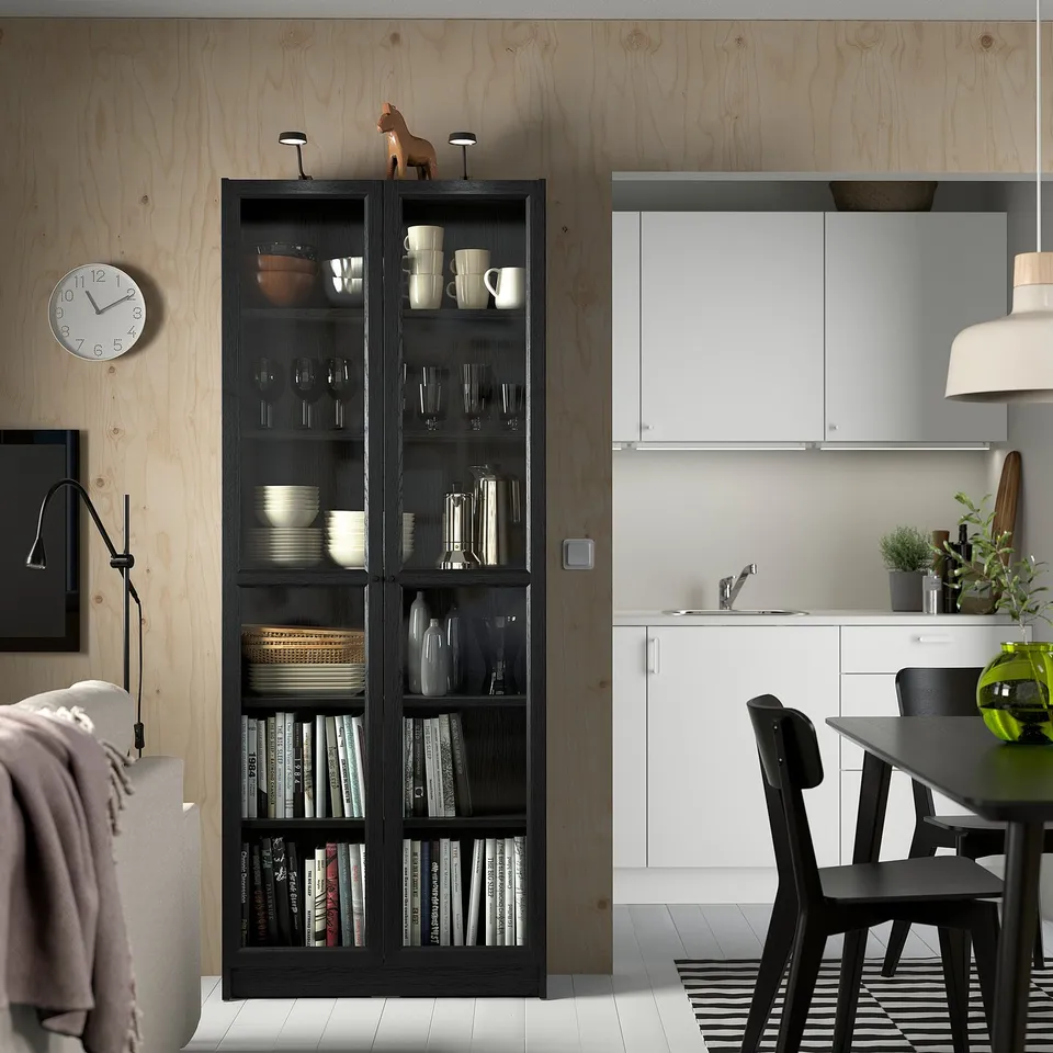 Modern living room with tall BILLY bookcase, books, decor, clock, and lamp.
