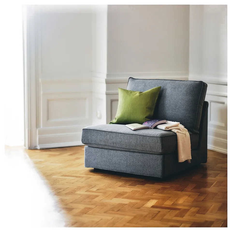 Modern grey sofa-bed with green pillow, wooden floor, minimalist design.