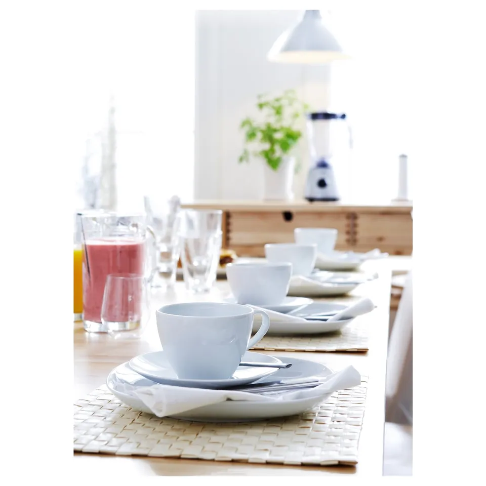 Table set with white VÄRDERA porcelain, square cups, plates, and napkins on woven placemats.