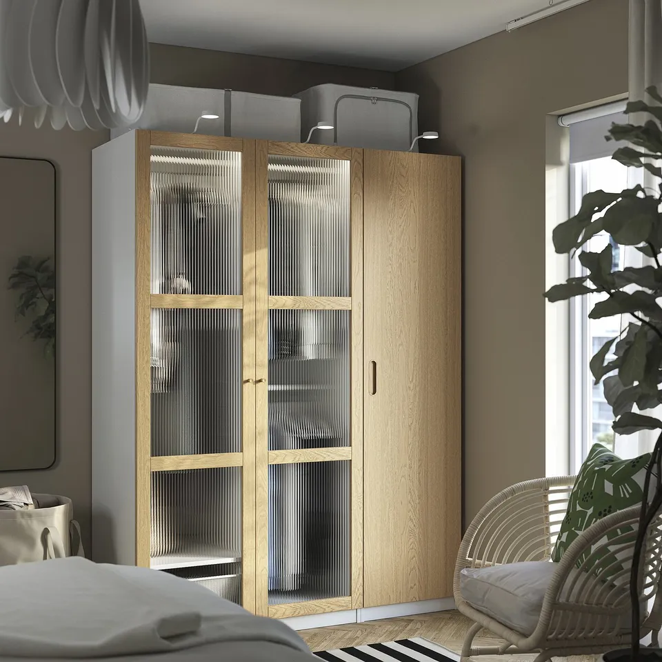 Modern bedroom with TONSTAD glass door wardrobe, wicker chair, and large window.