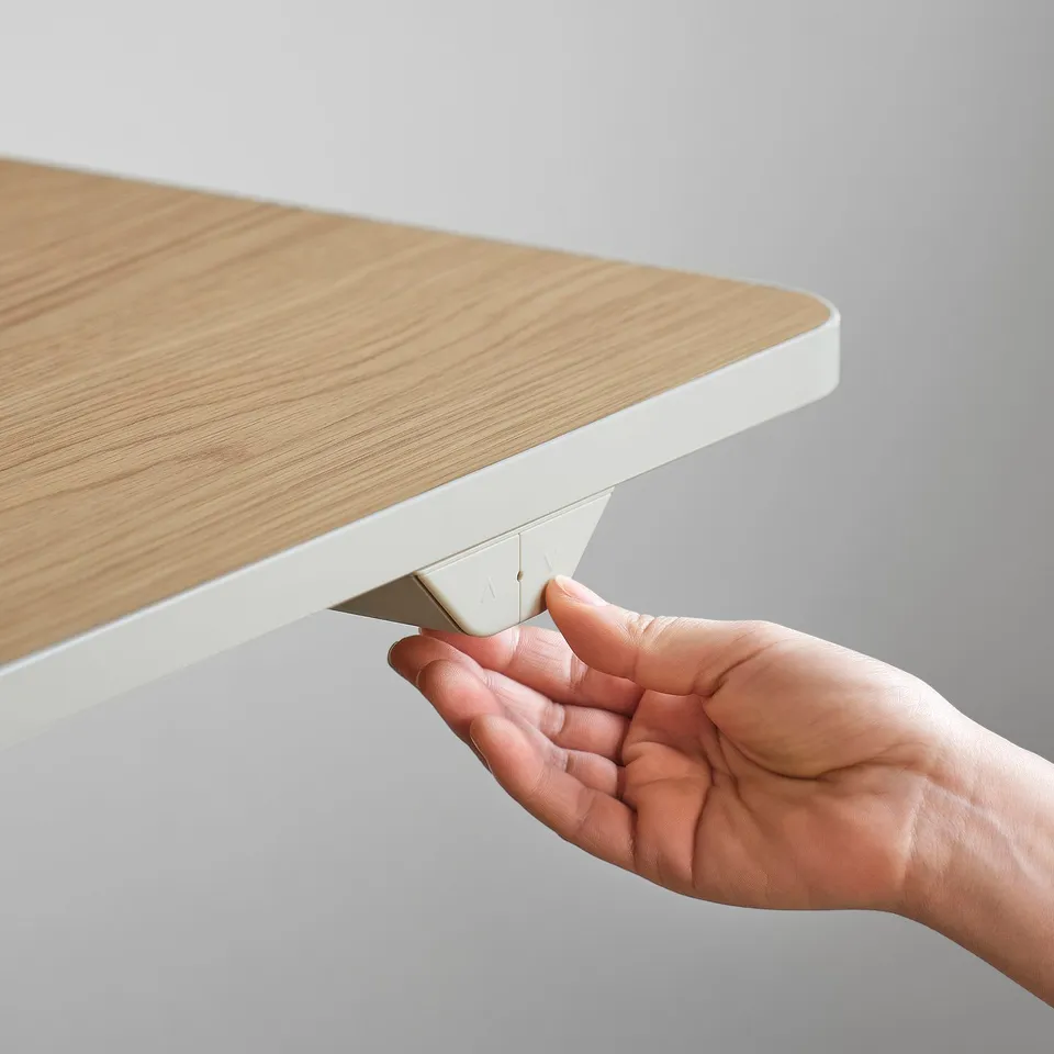 A hand adjusts a standing desks control panel, showcasing its height adjustment feature.