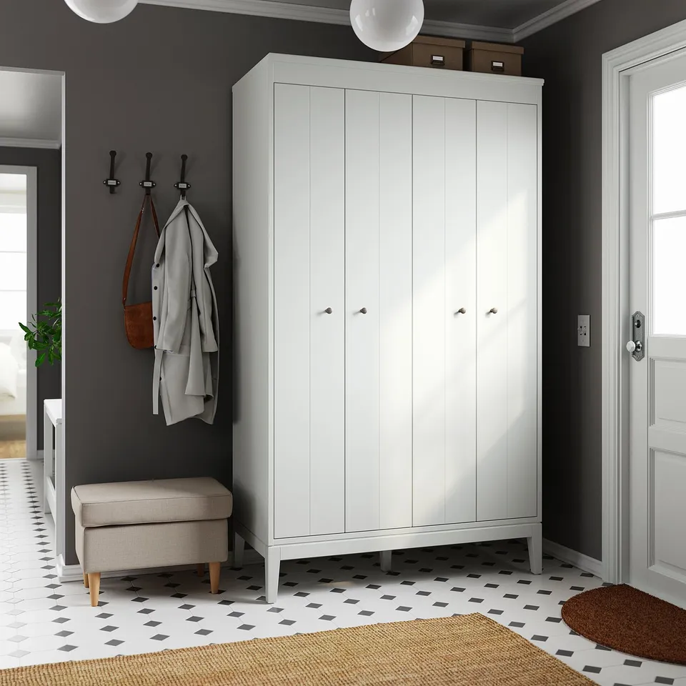 Modern entryway with white IDANÄS wardrobe, grey jacket, hooks, beige stool, black-and-white flooring, wooden mat, dark grey walls.