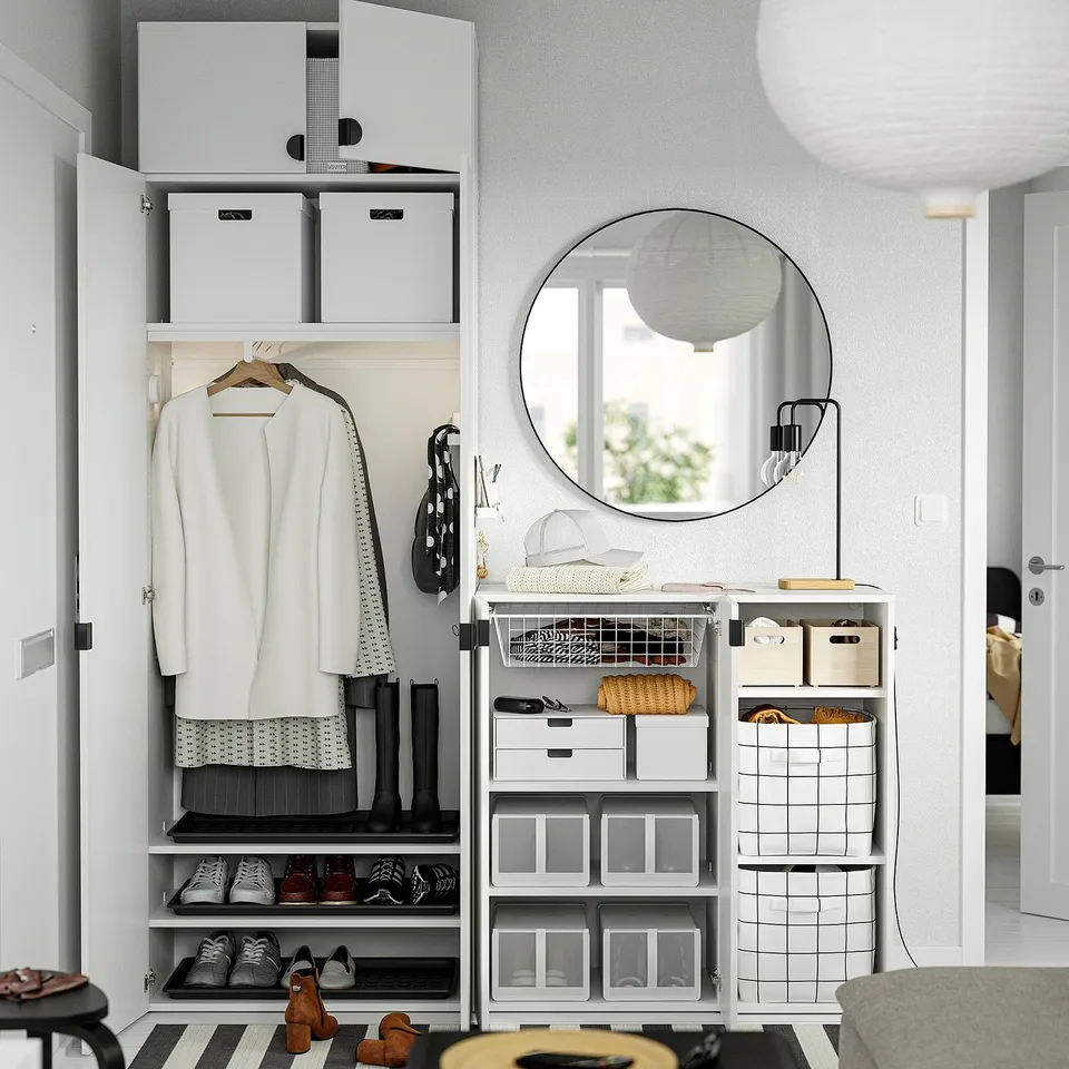 Modern closet with adjustable shelves, hanging clothes, and storage boxes, complemented by a round wall mirror and secure wall attachment.