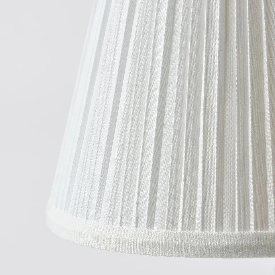 Close-up of a pleated, white fabric lampshade. Soft folds create a textured, elegant design. Perfect for diffusing gentle light.