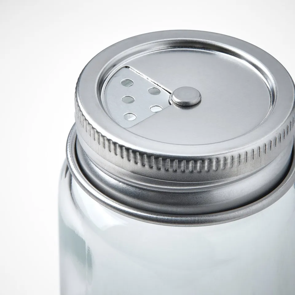 Clear glass jar with metallic lid, featuring a small dispenser window and an easily visible label for convenient viewing.