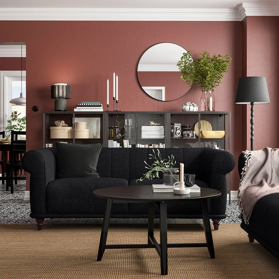 Dark grey VISKAFORS sofa with rounded shape & deep seat, black coffee table, red wall, mirror, floor lamp, & bookshelf with decor.