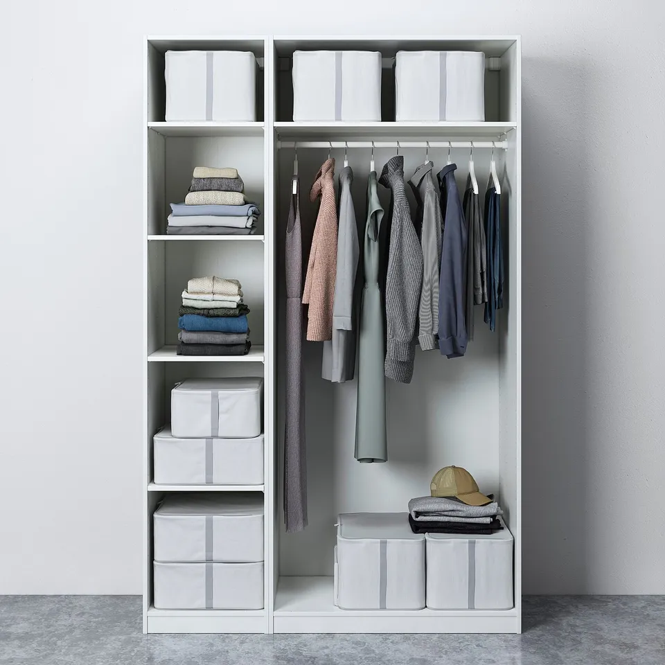 Modern closet with grey clothes, folded stacks, and striped boxes on white shelves.