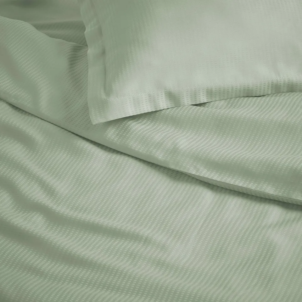 Elegant green bedding set with subtle pattern, smooth and cosy texture.