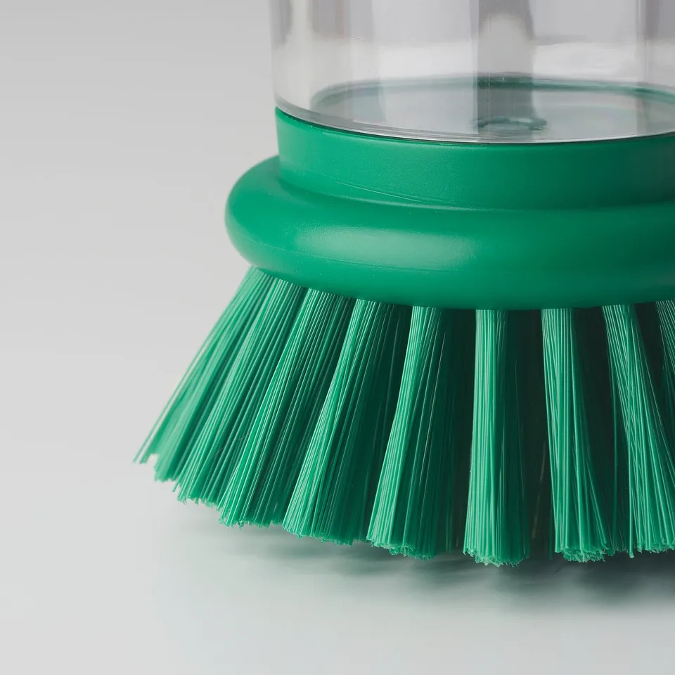Green dish brush with transparent handle, pressure system for soap, dense bristles.