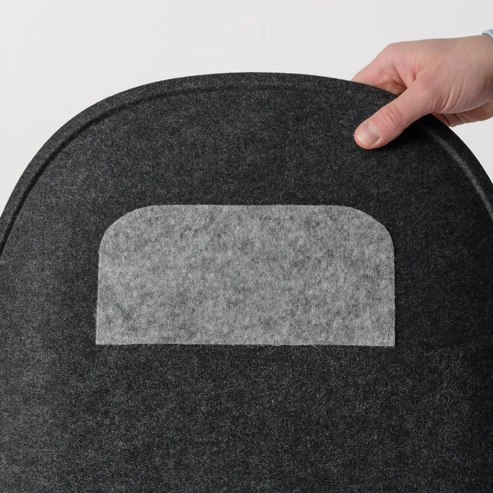Hand placing soft, black PYNTEN seat pad with non-slip back on white surface.