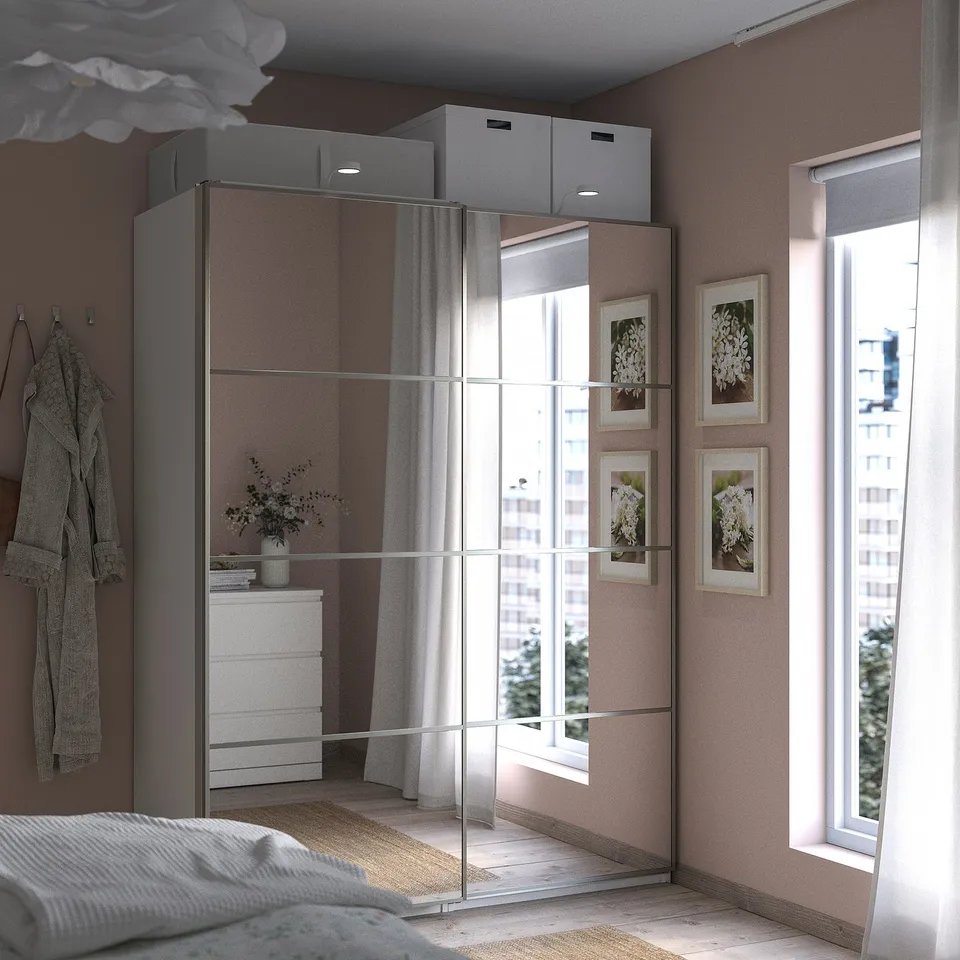 Modern bedroom with mirrored PAX wardrobe, large window, and cosy bed.