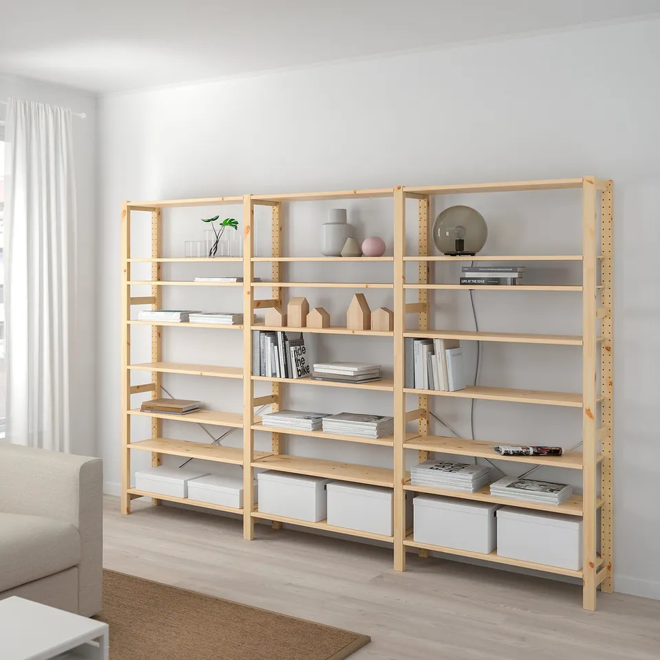 Large wooden IVAR shelves hold books and decor near a window.