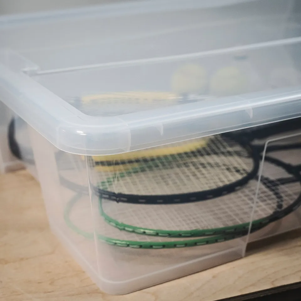 Clear plastic container with lid, holding two tennis rackets, showcasing its sturdy and transparent design.