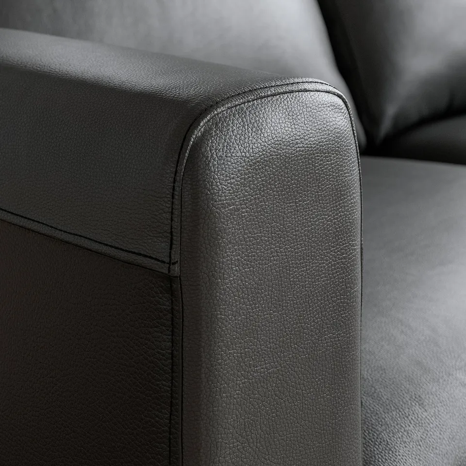 Close-up of high-quality black leather sofa, showcasing smooth, pebbled texture and clean stitching.