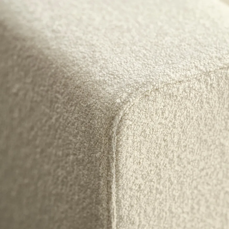 Close-up of soft, beige fabric. High-quality texture and meticulous stitching, emphasising comfort and craftsmanship.