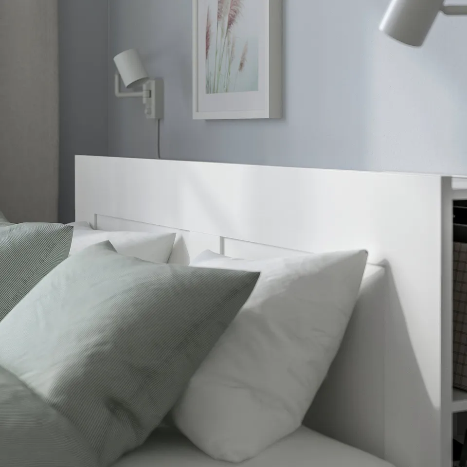 Bed frame with high headboard and integrated wall lights. The headboard has storage compartments for organising items.