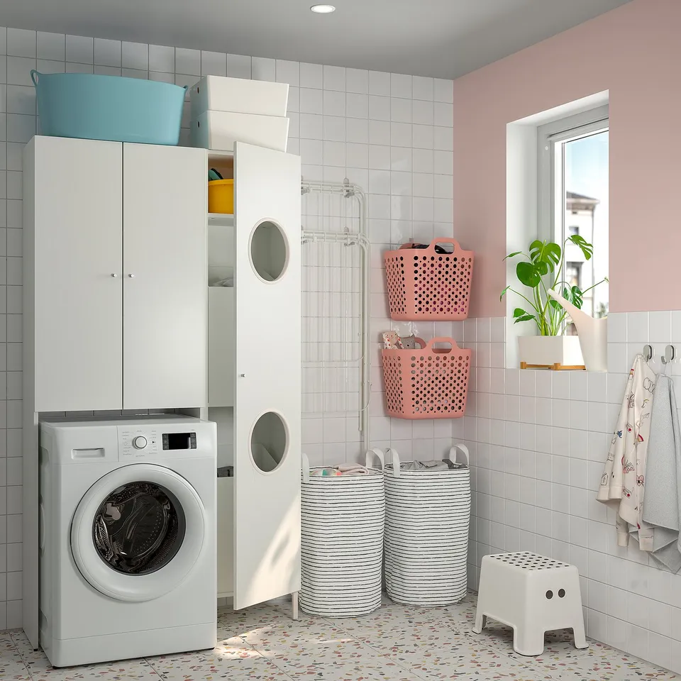 Modern white laundry room with NYSJÖN units, grey/pink baskets, washer, cabinets, and plants.