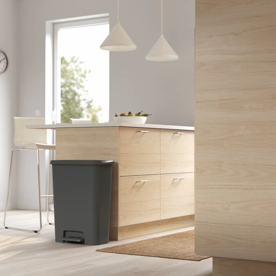 Modern kitchen with light wood cabinets and black KNÖCKLA bin with soft-close lid.