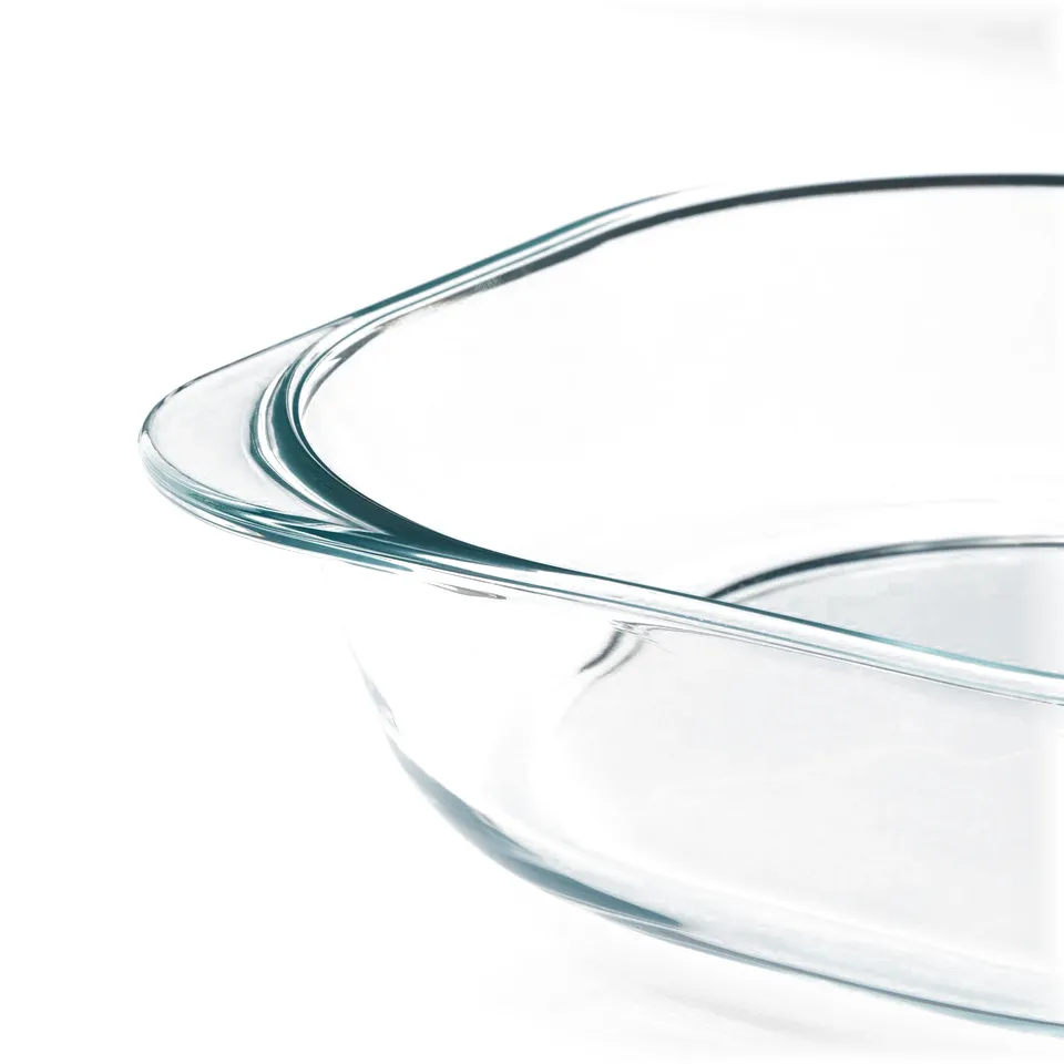 Clear, glass dish with curved, smooth edges on a white surface, showcasing its sleek design and transparency.