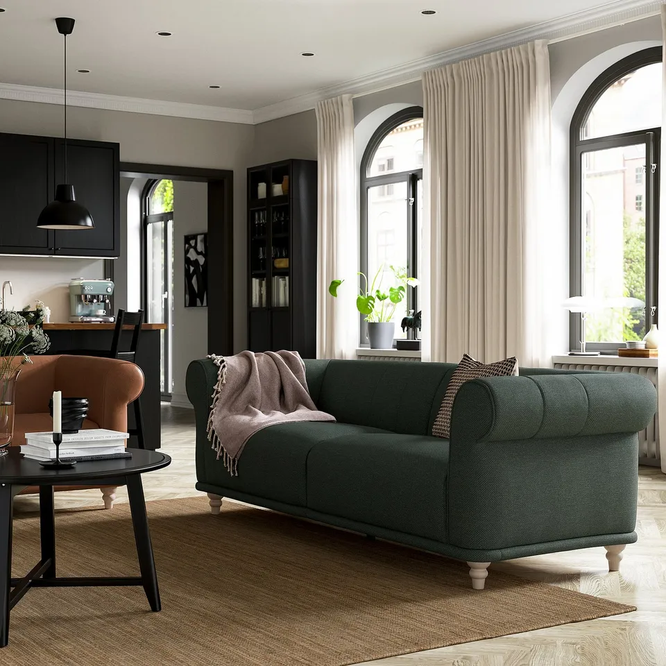 Green VISKAFORS sofa in cosy room with wooden floor and window.