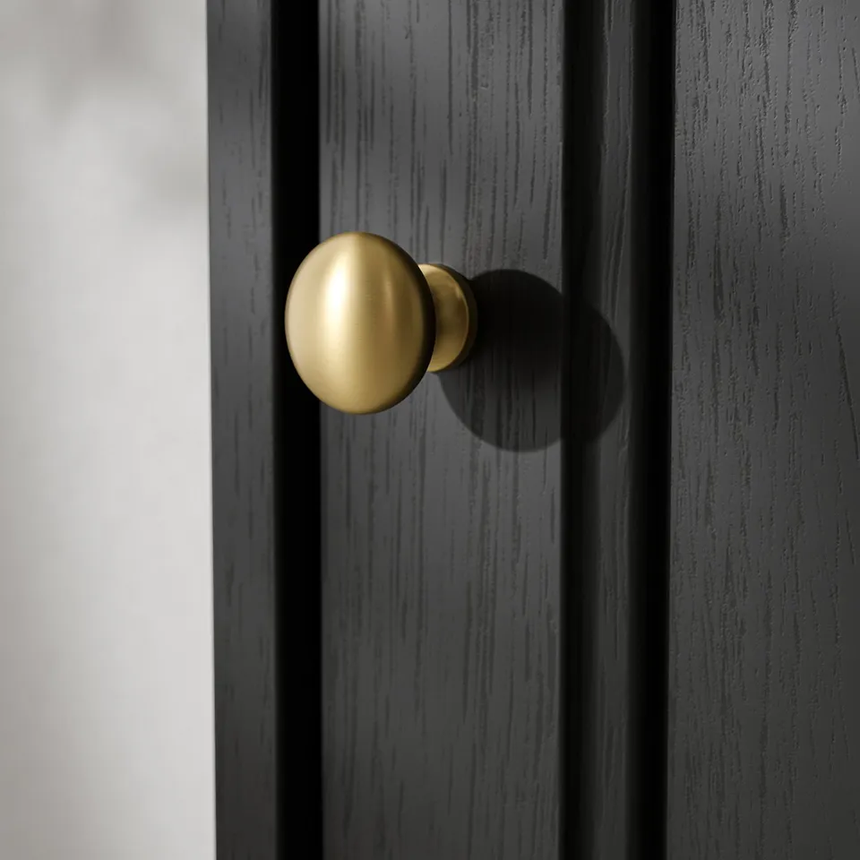 Close-up of sleek, gold-colored knobs on smooth, dark wood furniture, emphasising quality and design.