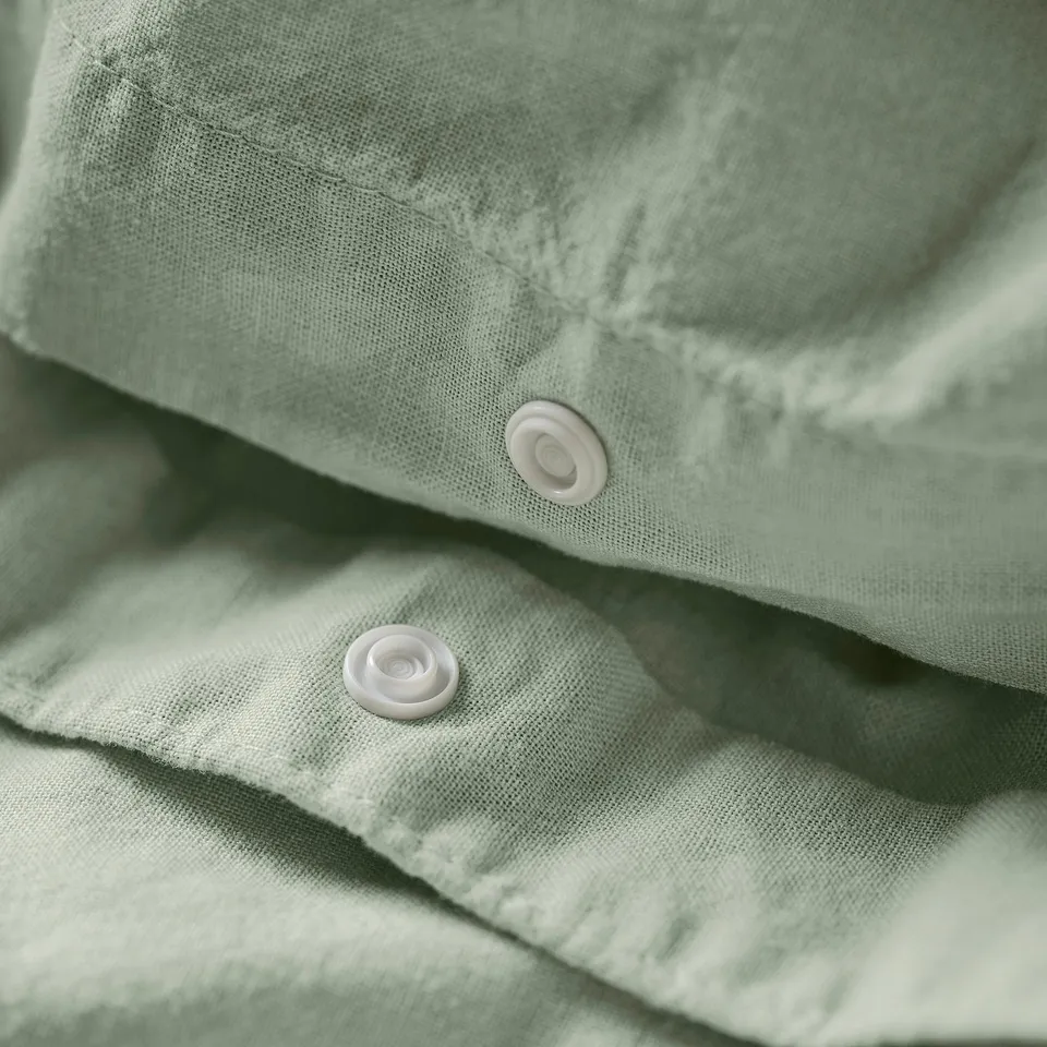 Close-up of green duvet cover with two white snap buttons.