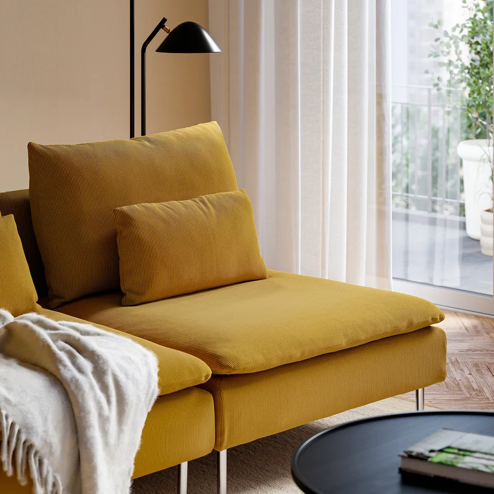 Mustard-colored modern couch with a black floor lamp beside it. Soft cushions for comfortable seating. Perfect for relaxation in a cosy setting.