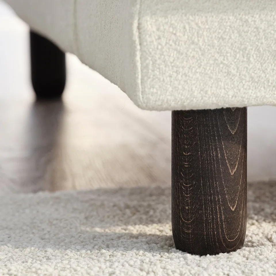 Modern sofa leg detail: slim, dark wood, smooth finish.
