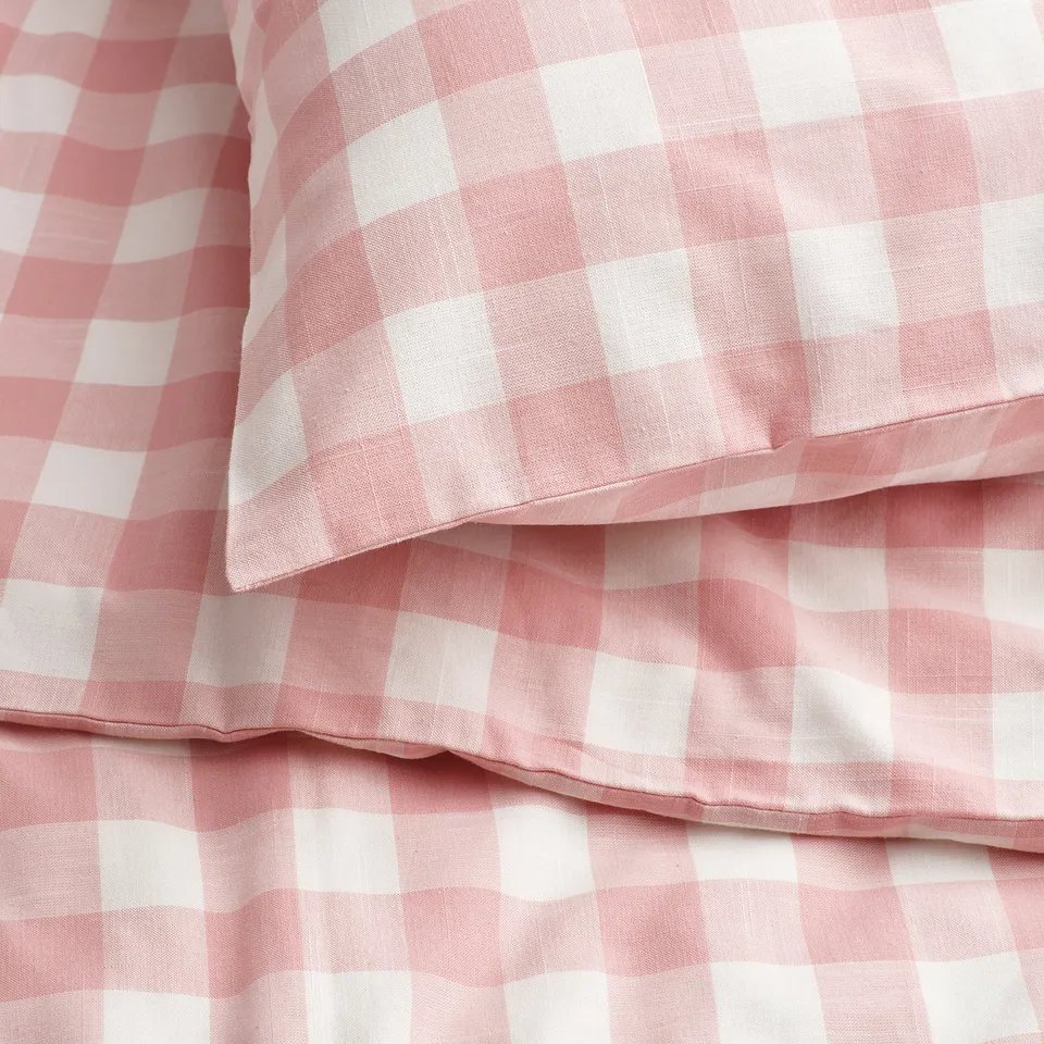 Close-up of light pink and white gingham check bedding, showcasing its soft, breathable texture.