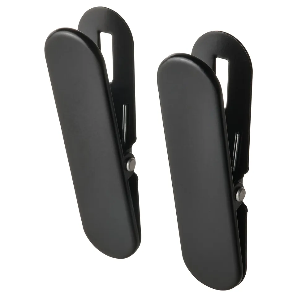 Two black, plastic, angled clips with holes for hanging items.