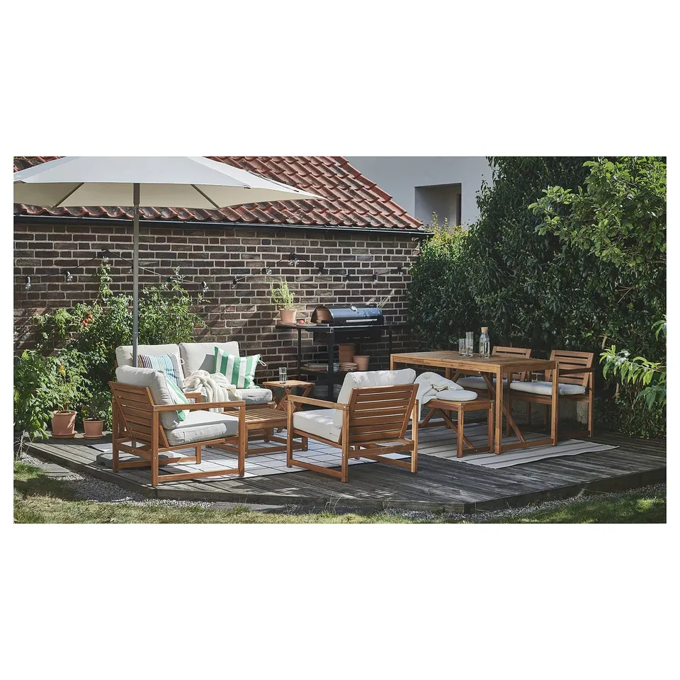 Patio with NÄMMARÖ wooden furniture, table, chairs, sofa, and white cushions on brick-paved area.