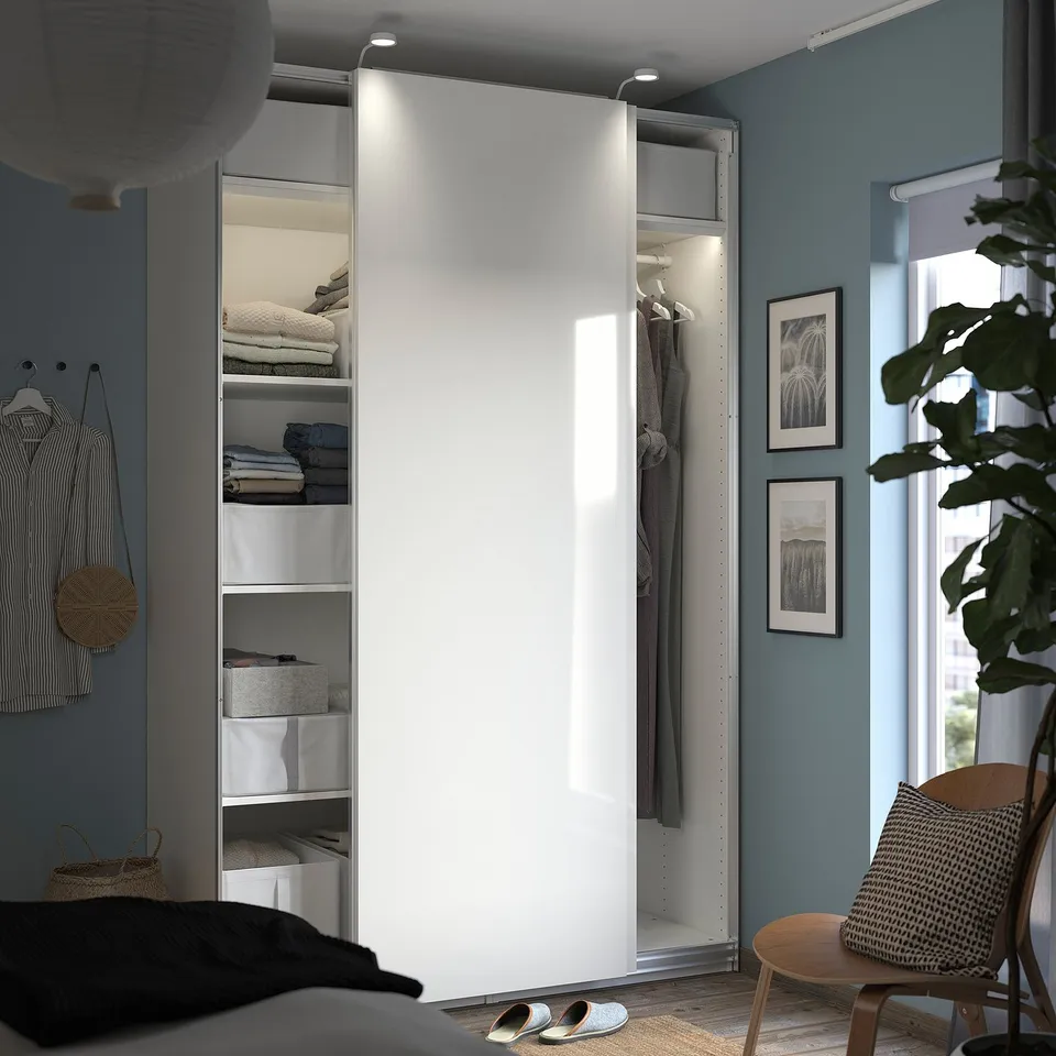 Modern blue bedroom with white PAX wardrobe, wooden chair, and green plant.