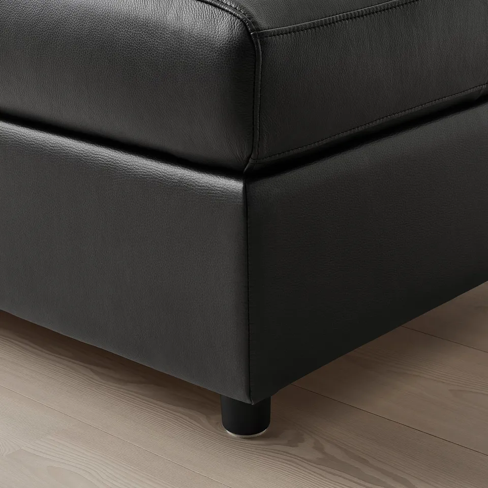Close-up of black leather sofa, showcasing smooth, high-quality material and sturdy stitching.
