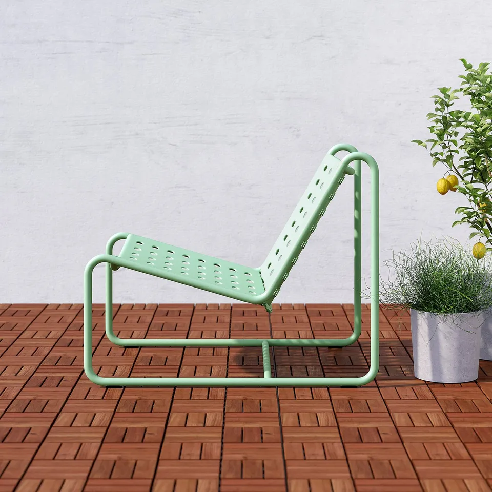 A green metal outdoor chair on a wooden deck, designed with a perforated seat and soft, rounded shapes for comfort and relaxation.