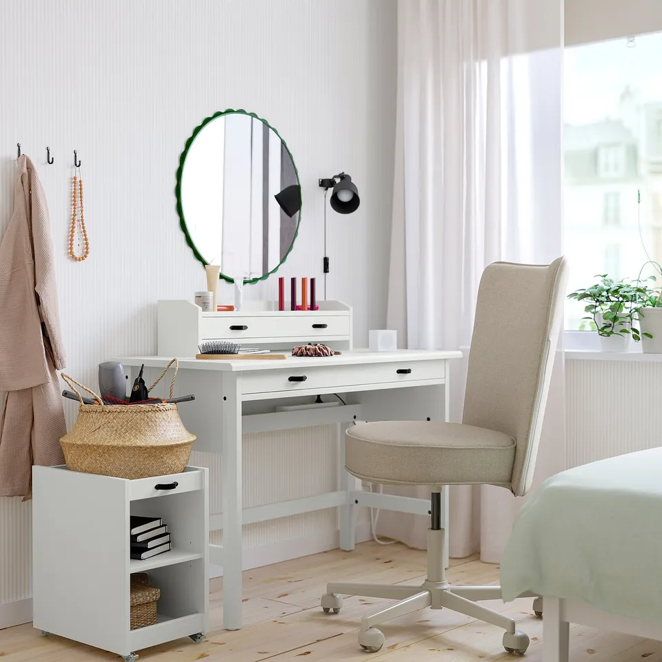 Minimalist workspace with white desk, green mirror, beige chair, and natural light.