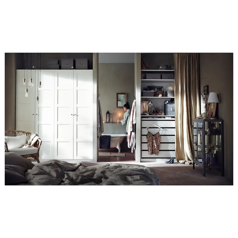 Modern bedroom with white PAX wardrobe, shelves, and a bathtub with candles.